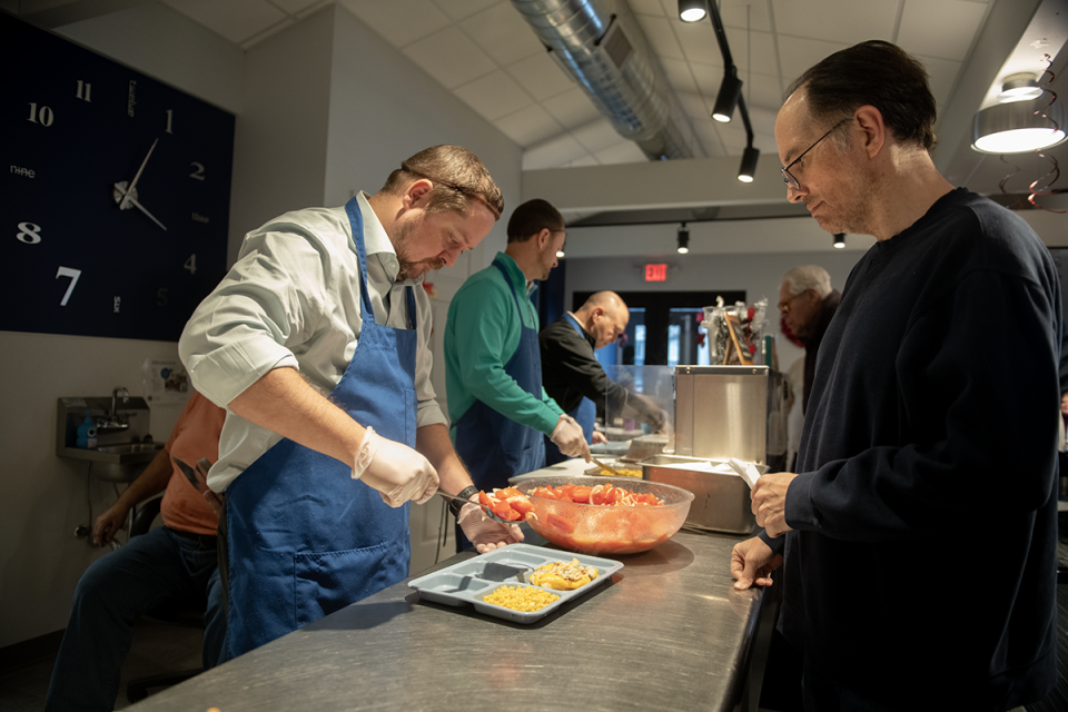 Bobby Dalton serves Matthias Hoefler during the hot meal service on Thursday, January 26.  Dalton, national sales manager for Kent Elastomers, voluteers at Kent Social Services along with coworkers Joe Williamson, vice president sales and marketing; and Brad Huntley, national sales manager.