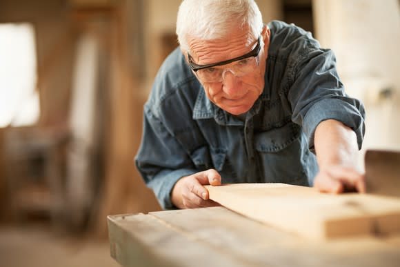 An elderly man working in a wood shop.