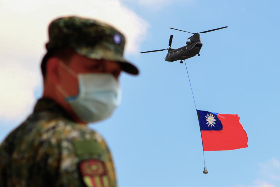 A Taiwanese soldier stands guard as a Chinook Helicopter carrying a Taiwan flag flies over a military camp, as part of a rehearsal for a National Day of Celebration in Taiwan last month. Source: Getty