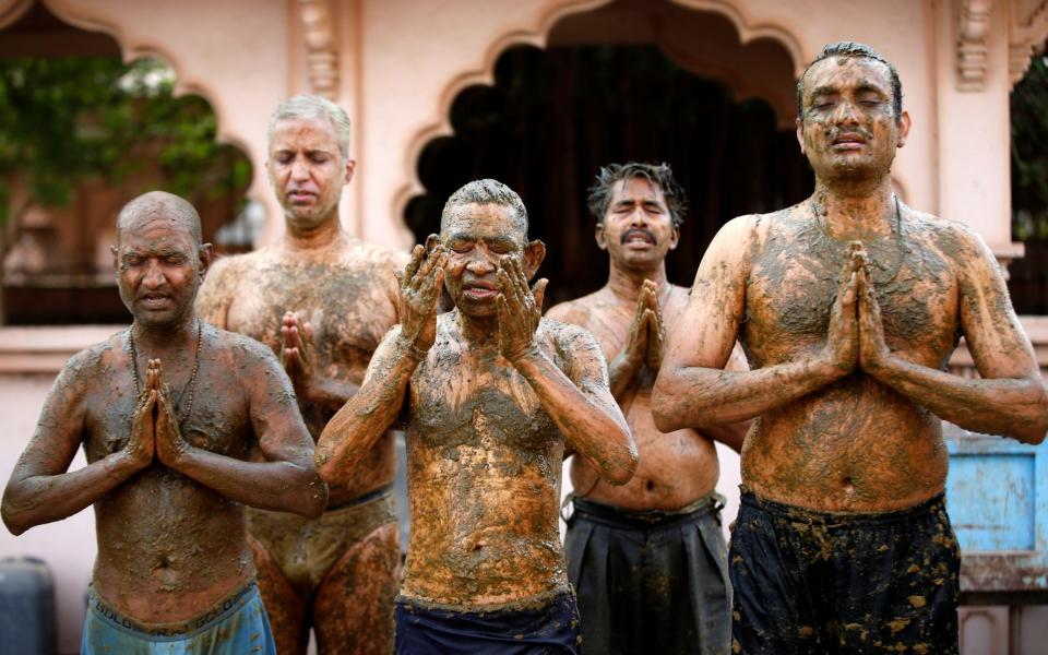 People pray after applying cow dung on their bodies during "cow dung therapy", believing it will boost their immunity to defend against the coronavirus disease (COVID-19) at the Shree Swaminarayan Gurukul Vishwavidya Pratishthanam Gaushala or cow shelter on the outskirts of Ahmedabad - Amit Dave/REUTERS