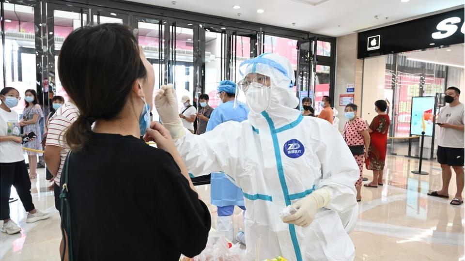 A medical worker collects a throat swab from a staff member for nucleic acid testing at Wanda Plaza on September 11, 2021 in Putian, Fujian Province of China.