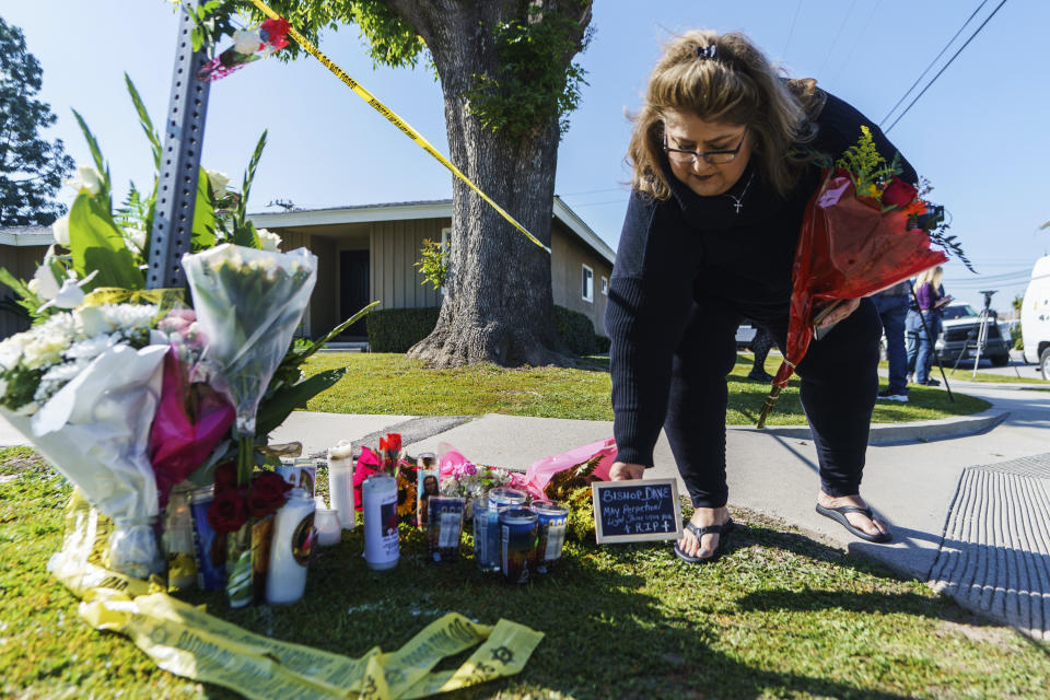 Ramona Torres brings flowers and a framed message to pay her respects to Bishop David O'Connell near his home in Hacienda Heights, Calif., Sunday, Feb. 19, 2023. O'Connell was shot and killed Saturday just blocks from a church, a slaying of a longtime priest hailed as a “peacemaker” that's stunned the Los Angeles religious community, authorities said. Detectives are investigating the death as a homicide, according to the Los Angeles County Sheriff's Department. (AP Photo/Damian Dovarganes)