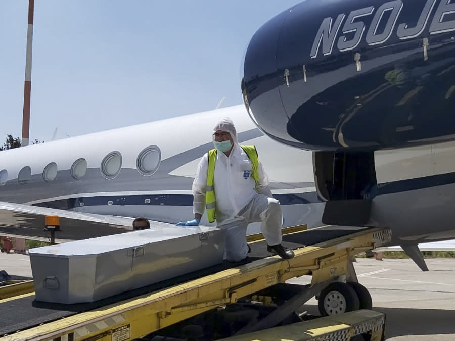 In this Monday, April 27, 2020 photo released by ZAKA, a voluntary emergency team, a member unloads a coffin from a plane at Ben Gurion airport in Israel. Air travel to Israel has come to a near standstill due to coronavirus restrictions, but one type of voyage still endures: the final journey of Jews wishing to be buried in Israel. Families, the aviation industry and health workers are finding ways to keep the deceased flying in despite the challenges presented by the virus. (Michael Gutwein, ZAKA via AP)