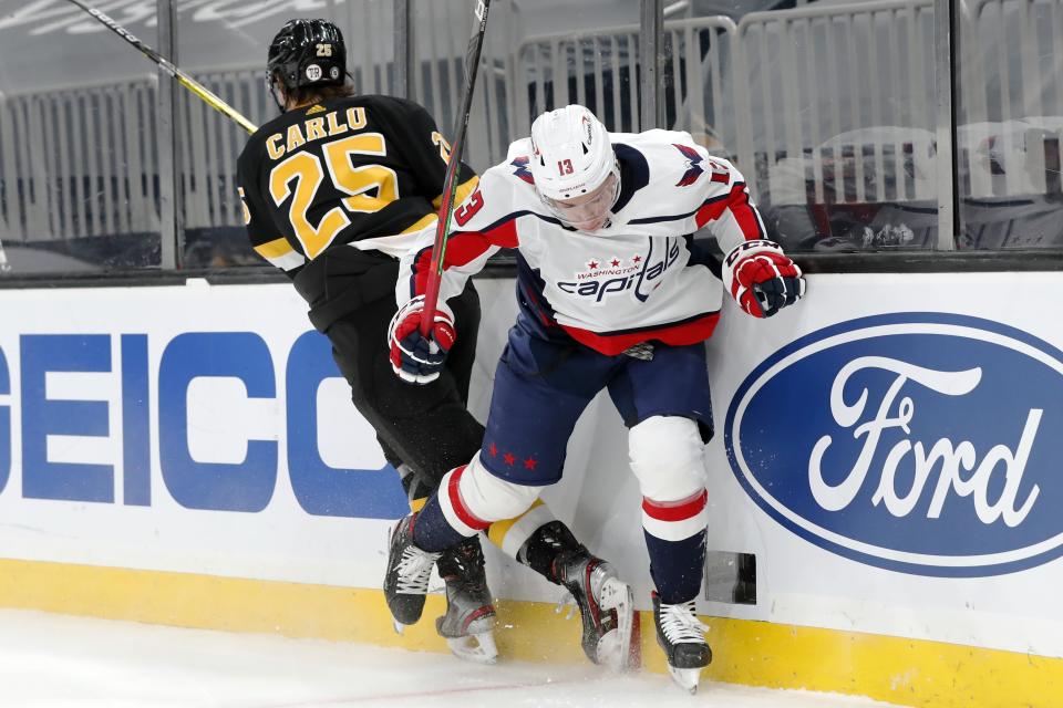 Boston Bruins' Brandon Carlo (25) checks Washington Capitals' Jakub Vrana (13) during the first period of an NHL hockey game Friday, March 5, 2021, in Boston. (AP Photo/Michael Dwyer)