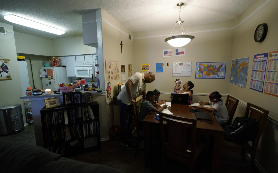 Arlena Brown, center, holds her youngest child, Lucy, 9 months, as she and husband, Robert, left, lead their other children, from left, Jacoby, 11; Felicity, 9, and Riley, 10, through math practice at their home in Austin, Texas, Tuesday, July 13, 2021. “I didn’t want my kids to become a statistic and not meet their full potential,” said Robert, a former teacher who now does consulting. “And we wanted them to have very solid understanding of their faith.” (AP Photo/Eric Gay)