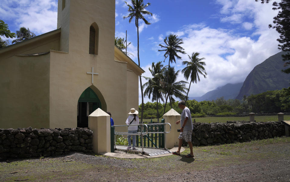 Kyong Son Toyofuku, left, her niece Yunra Huh, center, and husband, Lance Toyofuku, right, walk into St. Philomena Church during a tour of Kalaupapa, Hawaii, on Tuesday, July 18, 2023. The church was expanded and used by St. Damien and his parishioners in the 1800s while he lived with and cared for leprosy patients banished to Kalaupapa. (AP Photo/Jessie Wardarski)