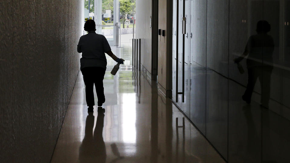 A worker from Boston University's maintenance department carries a bottle of sanitizer, due to concerns over the COVID-19 virus outbreak, while making her cleaning rounds at a campus building, Thursday, July 23, 2020, in Boston. Dozens of U.S. colleges are announcing plans to test students for the coronavirus this fall, but their strategies vary widely. Federal health officials discourage widespread testing on college campuses, but some researchers say it's necessary to prevent outbreaks. (AP Photo/Charles Krupa)