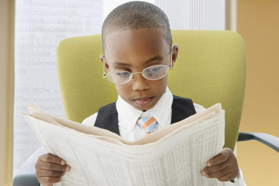 A little boy reading the newspaper