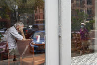 A woman wearing a face mask is reflected in the window of a coffee shop during the coronavirus pandemic in downtown Omaha, Neb., Friday, Aug. 7, 2020. (AP Photo/Nati Harnik)