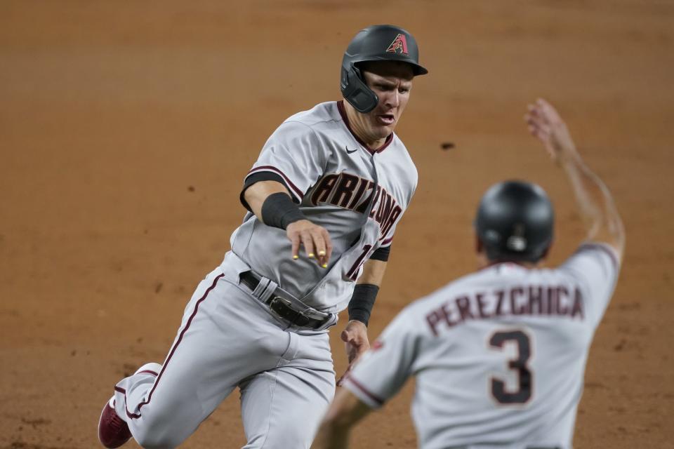 Arizona Diamondbacks' Daulton Varsho is waved home by third base coach Tony Perezchica to score on a Kole Calhoun double during the third inning of the team's baseball game against the Texas Rangers in Arlington, Texas, Tuesday, July 27, 2021. (AP Photo/Tony Gutierrez)