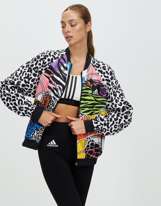  Woman with hair tied back wears animal print and brightly coloured Adidas Performance Rich Mnisi Tennis Woven Jacket, $160, over black leggings.
