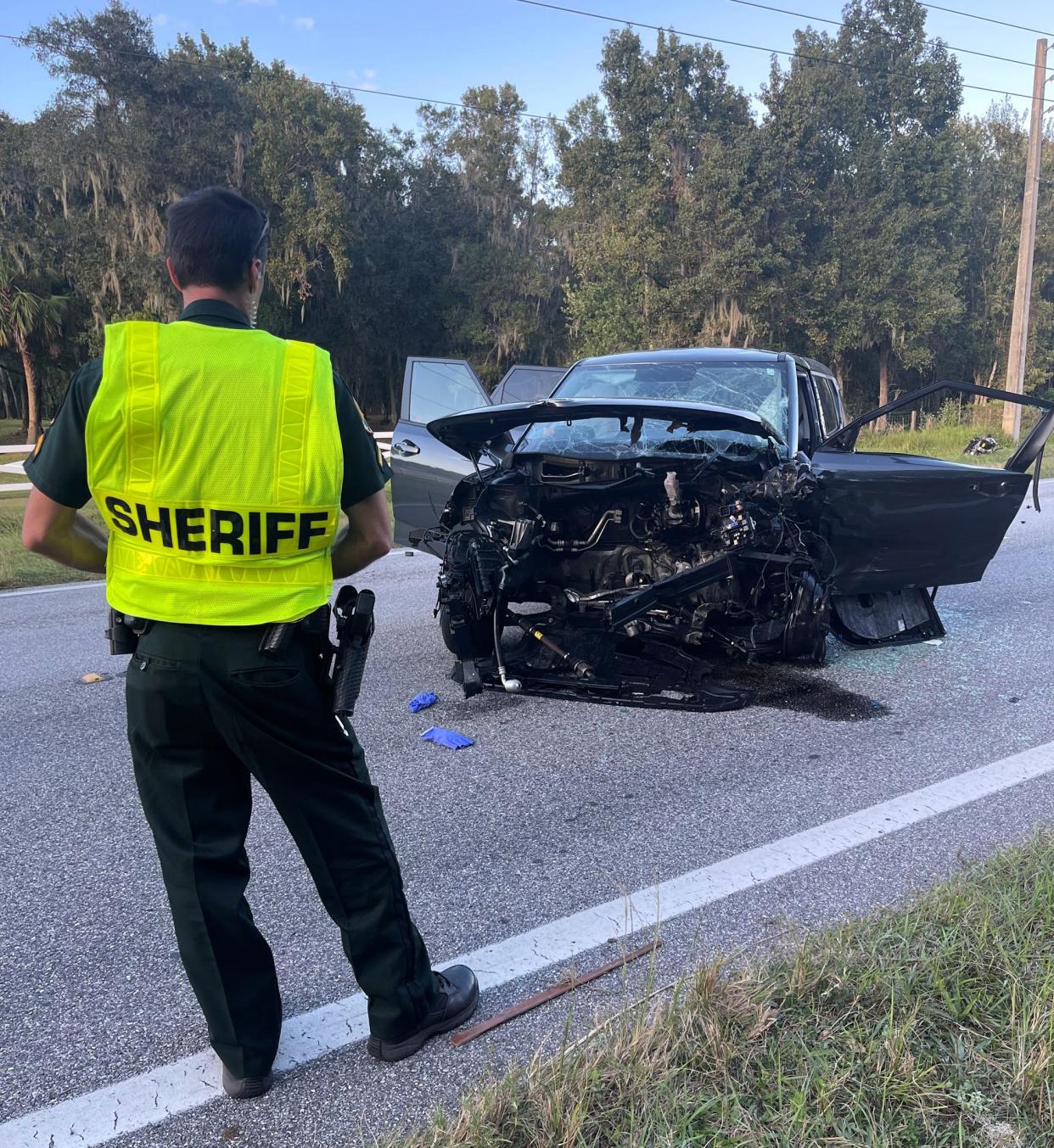 A Polk County Sheriff's Office employee stands near one of the vehicles involved in a deadly three-car collision Thursday afternoon.