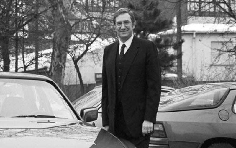 Porsche CEO Peter Schutz standing near cars in the 1980s, black and white photo