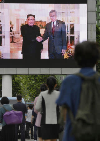 North Korean watch news report on North Korea's leader Kim Jong Un's Singapore visit in front of an electronic screen at Pyongyang station in Pyongyang, North Korea, in this photo taken by Kyodo June 11, 2018. Mandatory credit Kyodo/via REUTERS