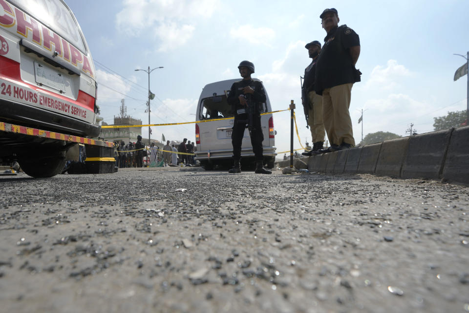 CORRECTS DATE - Police officers stand guard at the site of a suicide attack in Karachi, Pakistan, Friday, April 19, 2024. Five Japanese nationals traveling in a van narrowly escaped a suicide attack when a suicide bomber detonated his explosive-laden vest near their vehicle in Pakistan's port city of Karachi on Friday, wounding three passers-by, police said. (AP Photo/Fareed Khan)