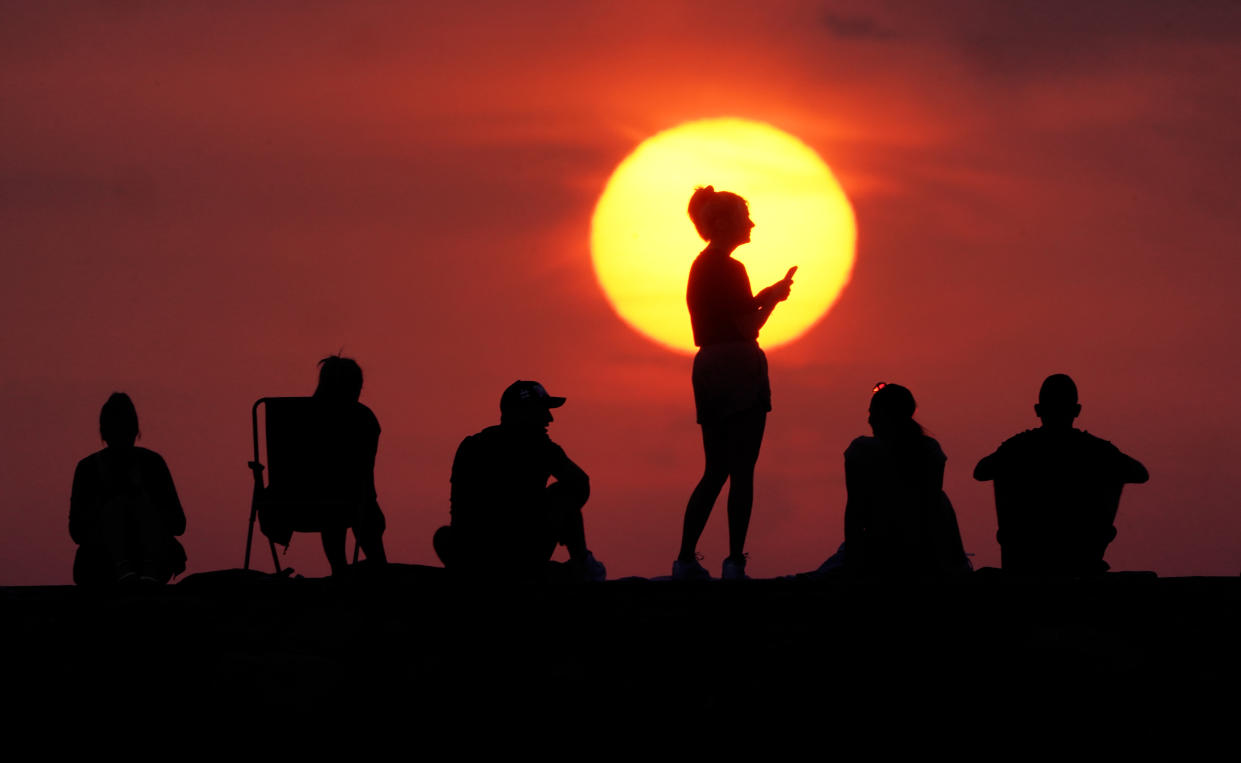 People turn out to watch the sunrise at Cullercoats Bay in North Tyneside as temperatures are predicted to hit 40°C (104°F). 