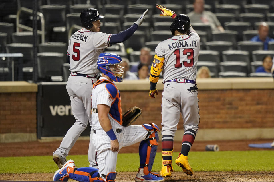 Atlanta Braves on-deck batter Freddie Freeman (5) greets teammate Ronald Acuña Jr. (13) after Acuña Jr. hit a solo home run during the fifth inning of the second baseball game of a doubleheader against the New York Mets, Monday, June 21, 2021, in New York. Mets catcher James McCann, center, looks on. (AP Photo/Kathy Willens)