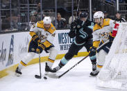 Nashville Predators forward Ryan O'Reilly, left, and forward Filip Forsberg work against Seattle Kraken' Brian Dumoulin for the puck during the second period of an NHL hockey game Saturday, March 16, 2024, in Seattle. (AP Photo/Stephen Brashear)