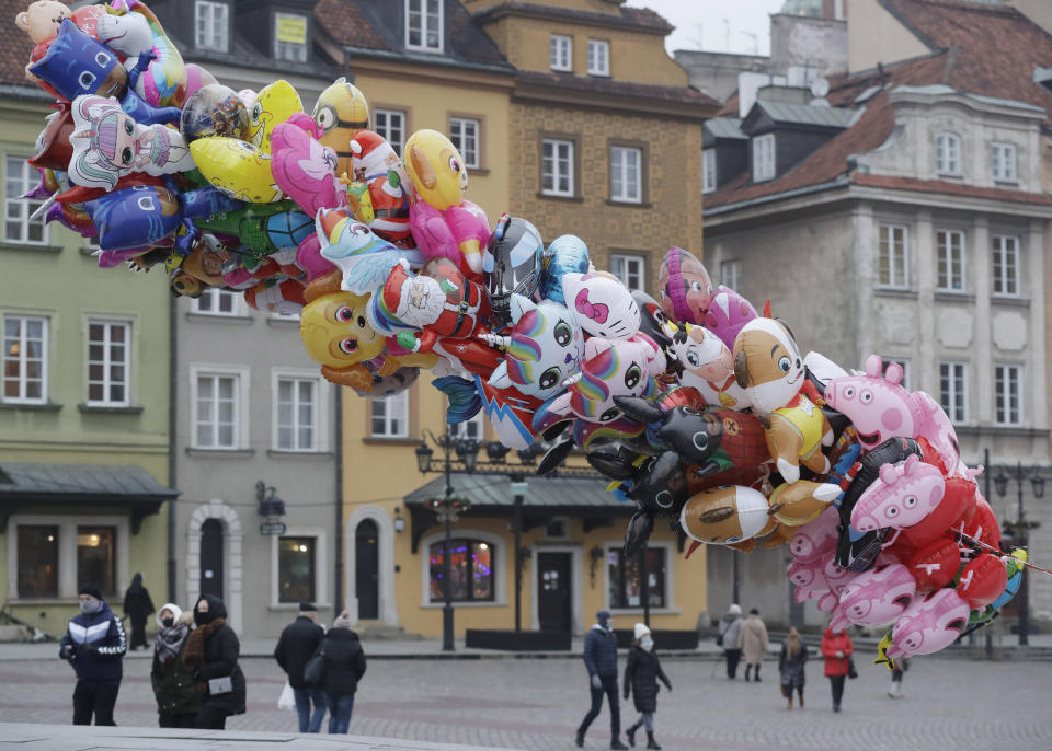 A balloon vendor waits for customers in usually bustling Warsaw's Castle Square that has few people now under anti-COVID-19 restrictions on New Year's Eve, in Warsaw, Poland, Thursday, Dec. 31, 2020.(AP Photo/Czarek Sokolowski)