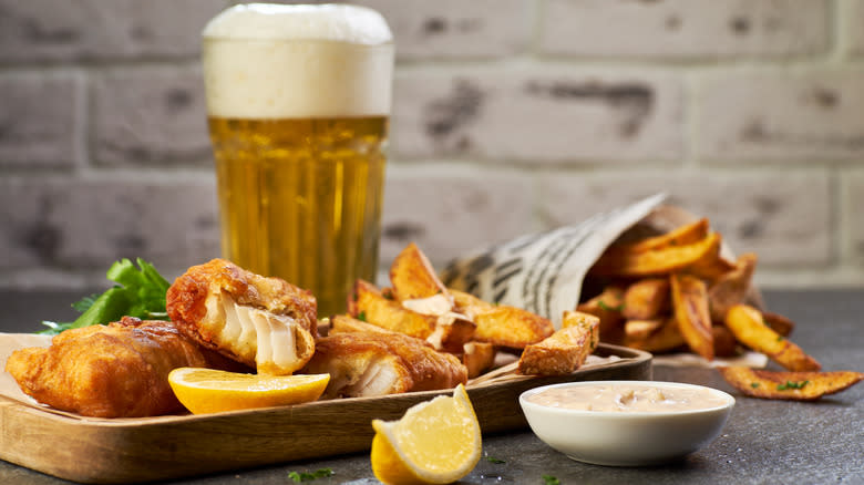 Tray of fish and chips before pint glass of beer