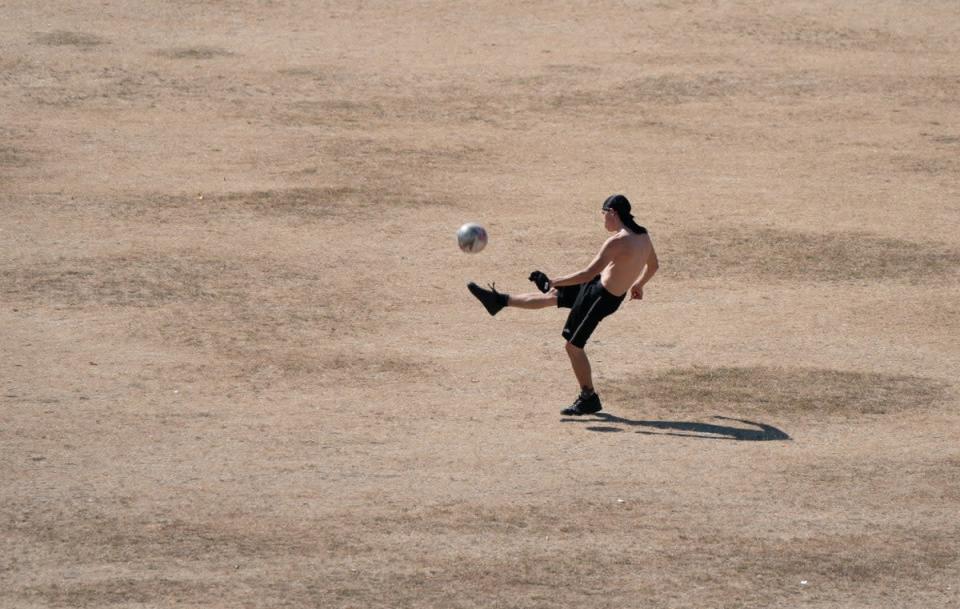 La gente juega al fútbol sobre la hierba reseca en Parker's Piece en Cambridge, ya que se ha declarado una sequía en partes de Inglaterra (Joe Giddens/PA).  (Cable PA)