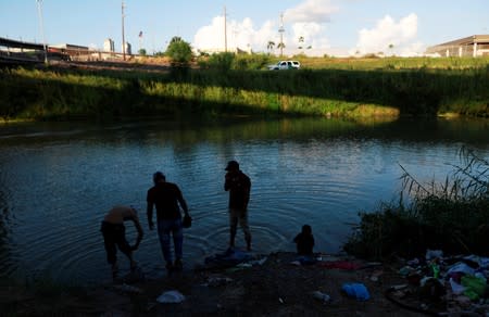 Central American migrants wash their clothes in the Rio Bravo near an encampment in Matamoros