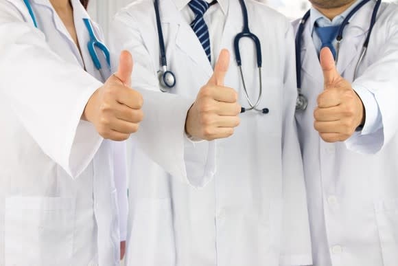 Three doctors giving thumbs-up signal.