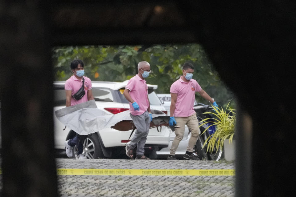 Funeral workers carry a victim's body at the Ateneo de Manila University in Quezon city, Philippines, Sunday, July 24, 2022. At least three people, including a former Philippine town mayor, were killed and another was wounded in a brazen attack on Sunday by a gunman in a university campus in the capital region, officials said. (AP Photo/Aaron Favila)