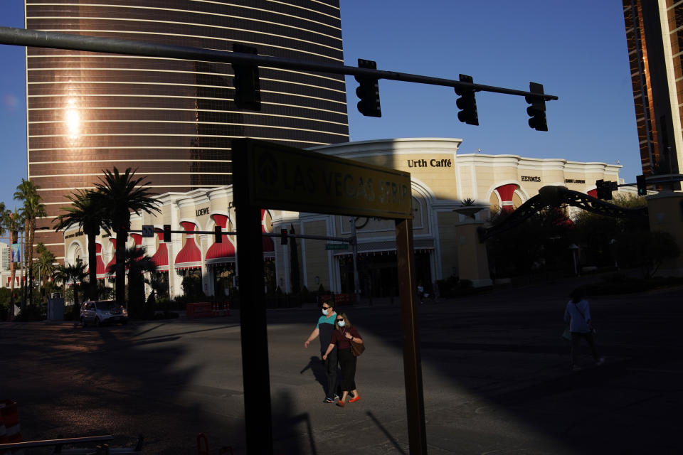 People cross Las Vegas Boulevard near the Wynn Las Vegas in Las Vegas, Feb. 10, 2021. Because of reduced visitation due to the coronavirus pandemic, the Wynn Resorts property Encore is closed during part of the week but open on weekends, with unused convention space repurposed as a coronavirus vaccination center operated by a public hospital. (AP Photo/John Locher)