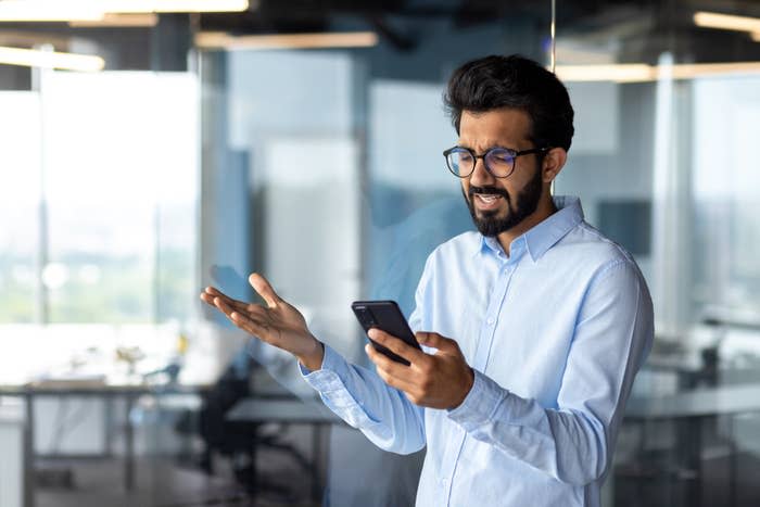 man looking at his phone in annoyance