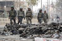 Security forces patrol past charred vehicles in a riot affected area following clashes between people demonstrating for and against a new citizenship law in New Delhi