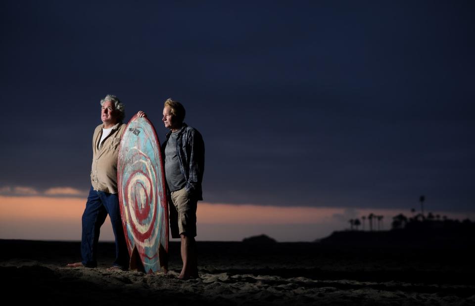 Surfers Kevin Naughton, left, and Craig Peterson stand on the sand in Laguna Beach.