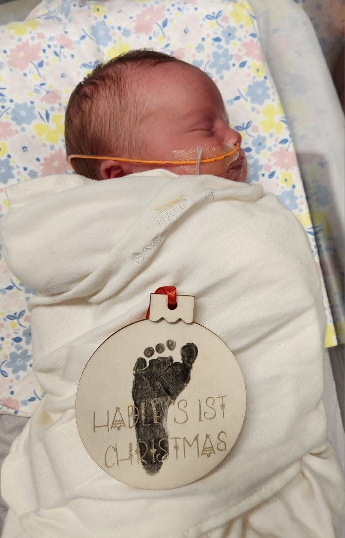 A "Hadley's 1st Christmas" ornament decorated with her footprint lays on Hadley.