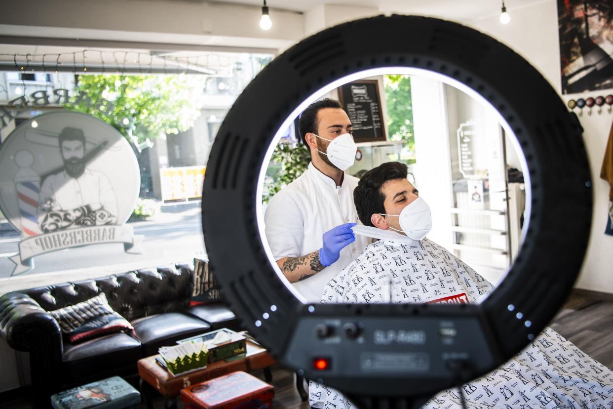 A hairdresser, wearing a protective face mask, cuts the hair of a client at the "La Barberia" shop in Lausanne, Switzerland on Monday, April 27, 2020. The Swiss authorities partly lifted the lockdown allowing people to reopen their shops after more than a month and a half of closing due to the coronavirus COVID-19.
