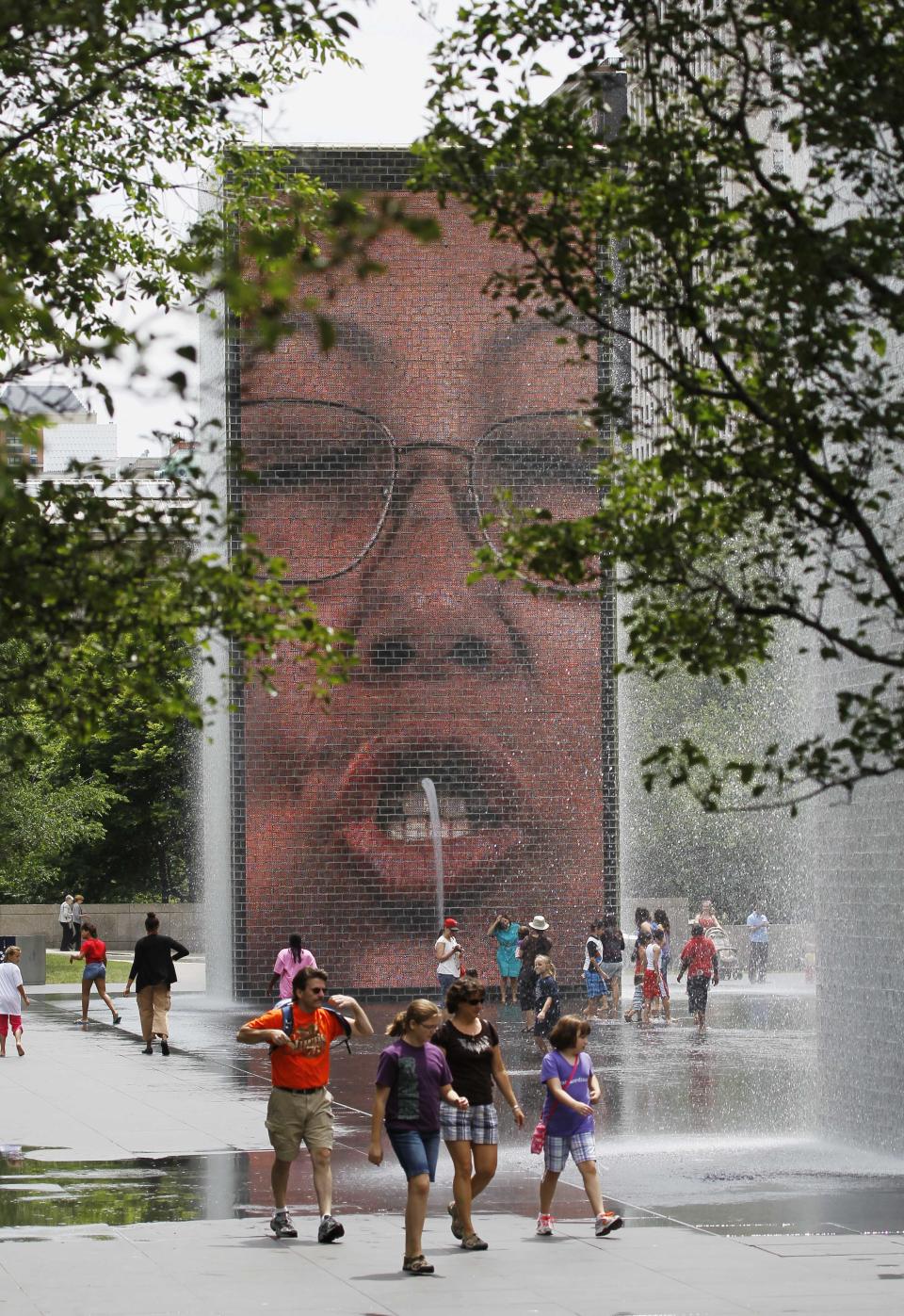 In this Wednesday, June 13, 2012 photo, visitors to Chicago's Millennium Park cool off by the Crown Fountain. Chicagoans consider Millennium Park and Grant Park the city's front yard. Both parks compromise hundreds of acres along southern Michigan Avenue filled with gardens, public art and views of the city and Lake Michigan.(AP Photo/Charles Rex Arbogast)