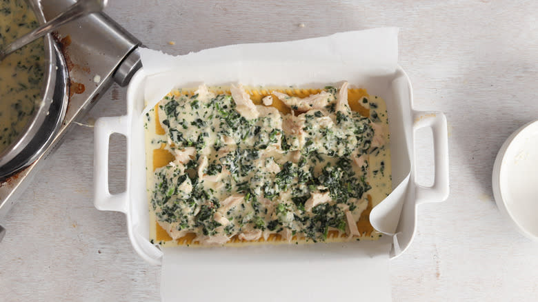 assembling chicken, spinach and cheese lasagna in baking dish