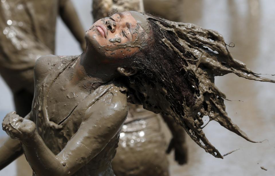 Jaylee Fogg, 10, throws back her mud crusted hair during Mud Day at the Nankin Mills Park, Tuesday, July 9, 2019, in Westland, Mich. The annual day is for kids 12 years old and younger. While parents might be welcome, this isn't an event meant for teens or adults. It's all about the kids having some good, unclean fun during their summer break and is sponsored by the Wayne County Parks. (AP Photo/Carlos Osorio)