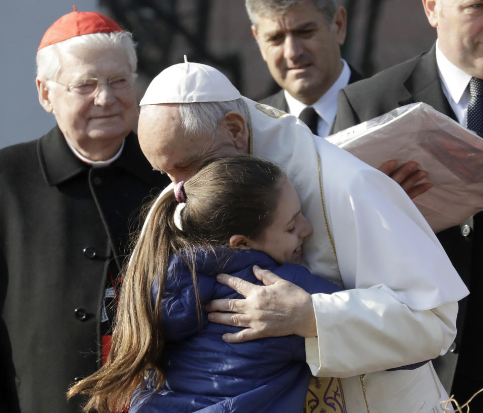 Pope Francis hugs a girls at Milan's Forlanini neighborhood known as Case Bianche (white houses), as part of his one-day pastoral visit to Monza and Milan, Italy’s second-largest city, Saturday, March 25, 2017. The pope's first stop Saturday is a housing project on the outskirts of Italy's fashion and finance capital, a stop that underlines the pope's view that the peripheries offer a better view of reality than well-tended and prosperous city centers. In the background at left is Cardinal Angelo Scola. (AP Photo/Antonio Calanni)