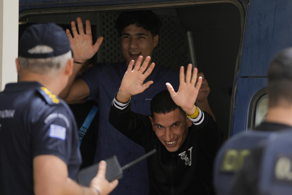 Two of nine Egyptians, who were on trial for migrant smuggling, wave to the media persons as they leave the court in Kalamata, southwestern Greece, on Tuesday, May 21, 2024. A Greek judge dismissed charges against nine Egyptian men accused of causing a shipwreck that killed hundreds of migrants last year and sent shockwaves through the European Union's border protection and asylum operations, after a prosecutor told the court Greece lacked jurisdiction. (AP Photo/Thanassis Stavrakis)
