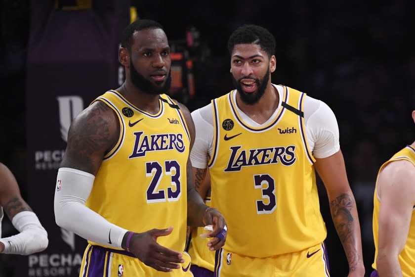 FILE - In this Feb. 21, 2020, file photo, Los Angeles Lakers forward LeBron James, left, stands with forward Anthony Davis during the second half of an NBA basketball game against the Memphis Grizzlies in Los Angeles. James and Davis had the Lakers on course to contend for another NBA title before the coronavirus pandemic upended their first season together. The superstars see no reason they can't continue their quest in Orlando, and Davis even thinks the Lakers' chances have improved.(AP Photo/Mark J. Terrill, File)