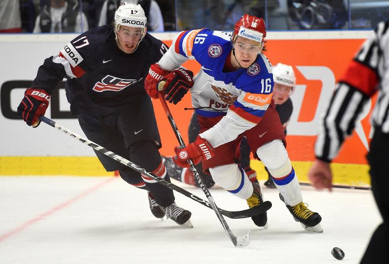 John Moore Jr (L) of the US and Russia's Sergei Plotnikov chase the puck during the group B preliminary round ice hockey match Russia vs USA on May 4, 2015 at the CEZ Arena in Ostrava