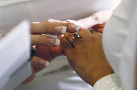 A woman puts a ring on the hand of another woman in a civil union ceremony after Colorado's civil union law went into effect in Denver May 1, 2013.REUTERS/Rick Wilking