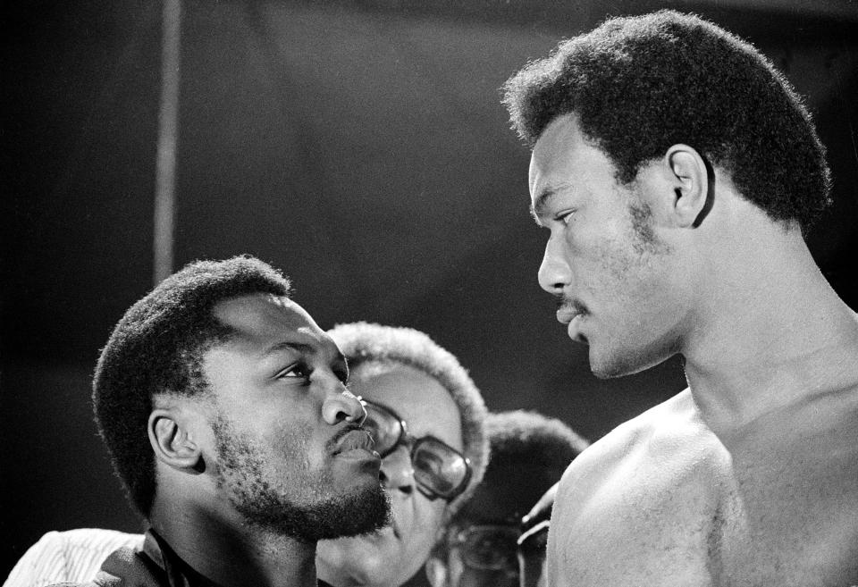 FILE - In this file photo taken Jan. 22, 1972, defending WBA champion Joe Frazier, left, and challenger George Foreman have a close look at each other as they meet during the weigh-in moments before their world heavyweight boxing title bout at National Stadium in Kingston, Jamaica. The former heavyweight champion has died after a brief final fight with liver cancer. He was 67. The family issued a release confirming the boxer's death on Monday, Nov. 7, 2011. (AP Photo/File)