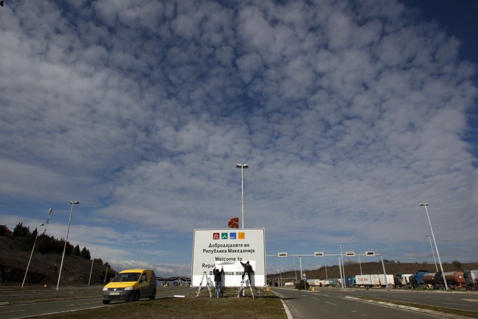 Workers replace signage with an adhesive banner in the southern border with Greece, near Gevgelija, North Macedonia, Wednesday, Feb. 13, 2019. Workers in the newly renamed North Macedonia have begun replacing road signs to reflect the change in their country's name, following a deal with neighboring Greece to end a nearly three decade-long dispute and secure NATO membership. (AP Photo/Boris Grdanoski)