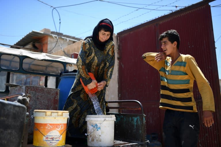 Al-Jassem fills a bucket with water for her grape vine on a visit to her home on July 15, 2017, five weeks after leaving during fighting between US-backed forces and Islamic State militants