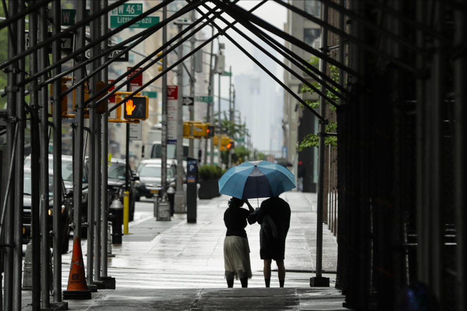 Pedestrians use an umbrella to protect themselves from the rain as they walk along Sixth Avenue during the coronavirus pandemic, Saturday, May 23, 2020, in New York. (AP Photo/Frank Franklin II)