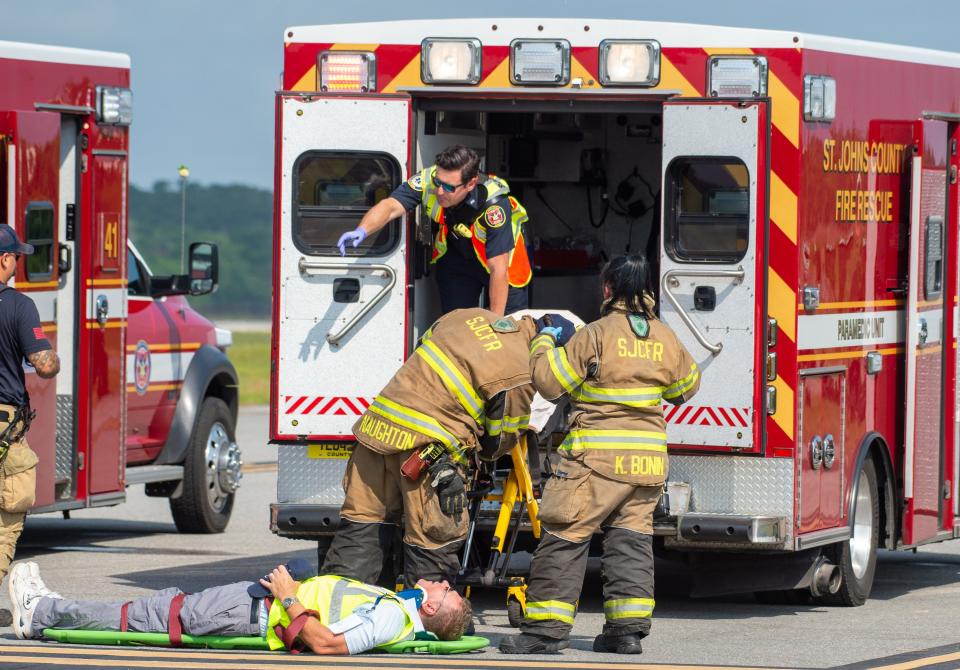 Firefighters and paramedics load a volunteer playing a victim of an airplane crash during a training exercise at the Northeast Florida Regional Airport in St. Augustine on Wednesday, May 18, 2022.  