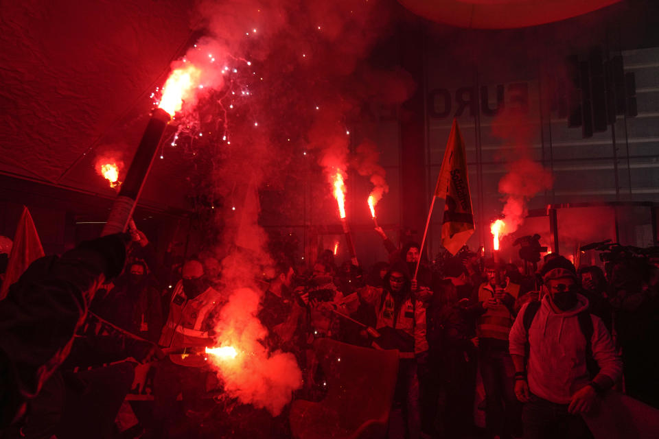 Demonstrators holding flares invading the Euronext Paris building in protest to the pension reforms at La Defense business district in Paris, Thursday, April 20, 2023. Union activists stage scattered actions to press France's government to scrap the new law raising the retirement age. (AP Photo/Thibault Camus)