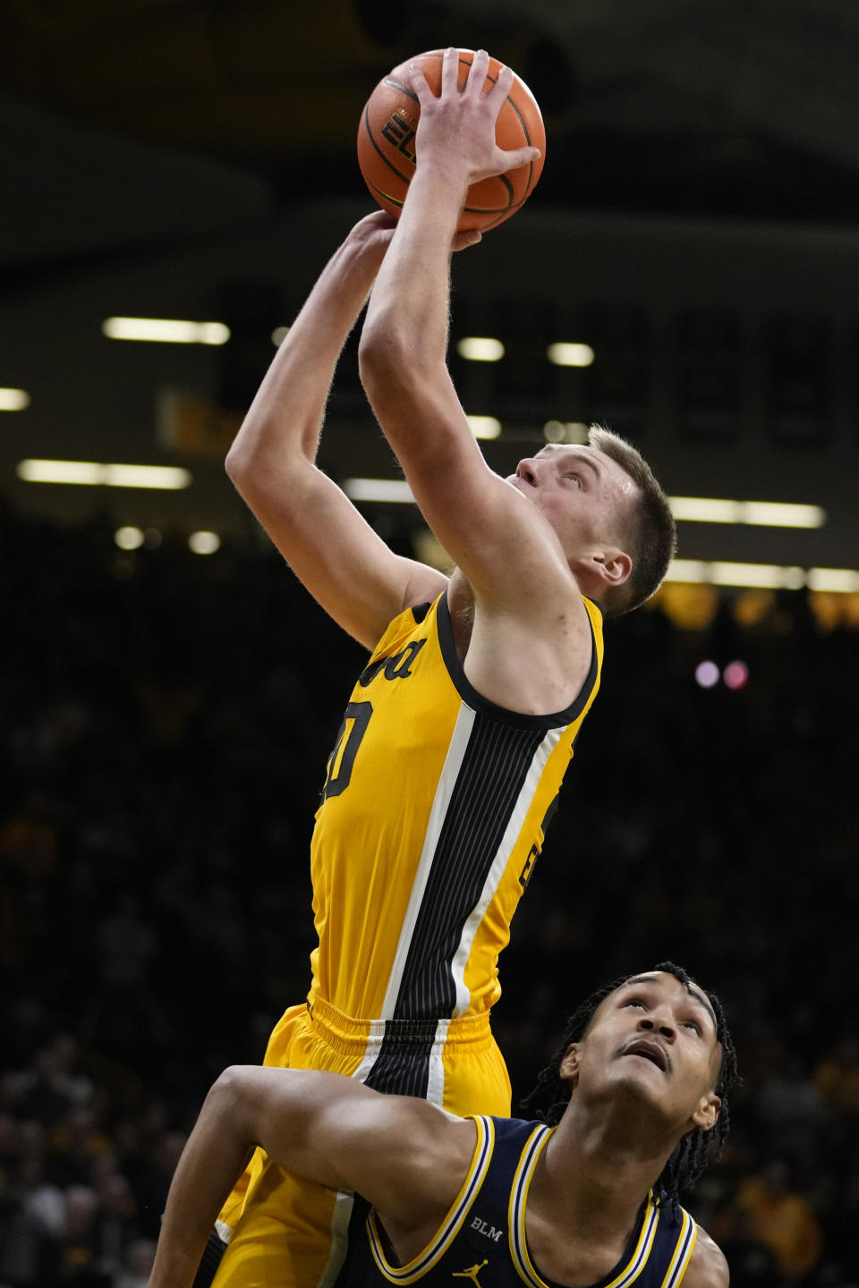 Iowa forward Payton Sandfort, top, is fouled by Michigan guard Dug McDaniel while driving to the basket during overtime in an NCAA college basketball game, Thursday, Jan. 12, 2023, in Iowa City, Iowa. Iowa won 93-84 in overtime. (AP Photo/Charlie Neibergall)