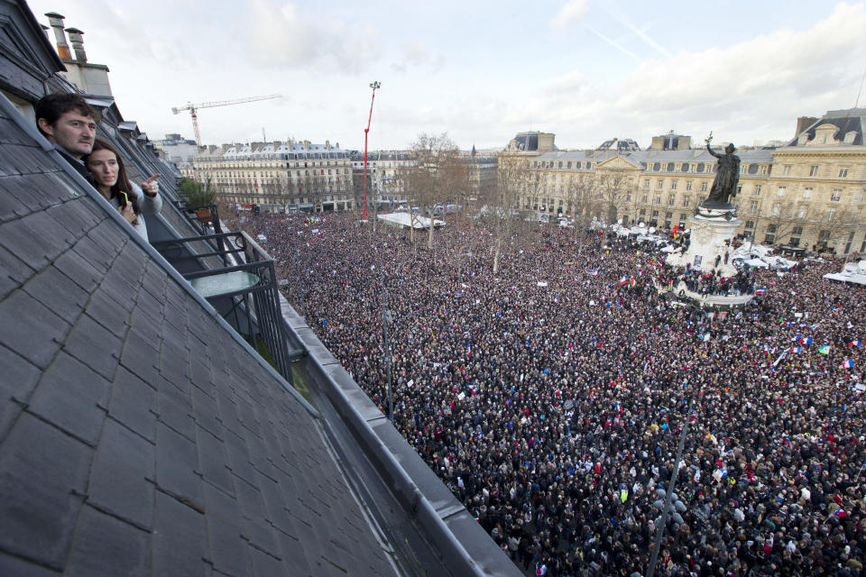 People watch from their roof-top apartment as some thousands of people gather at Republique square. (AP Photo/Peter Dejong)